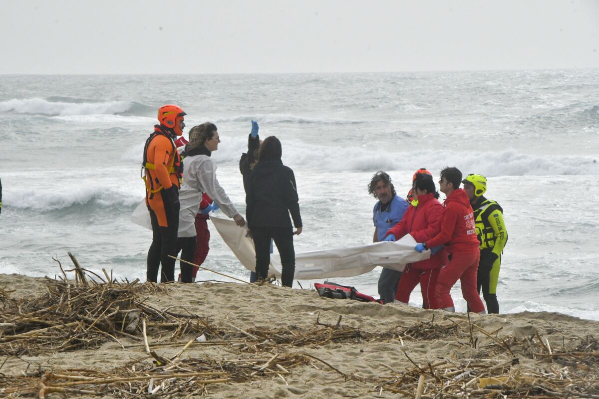 Rescuers carry a body at a beach.