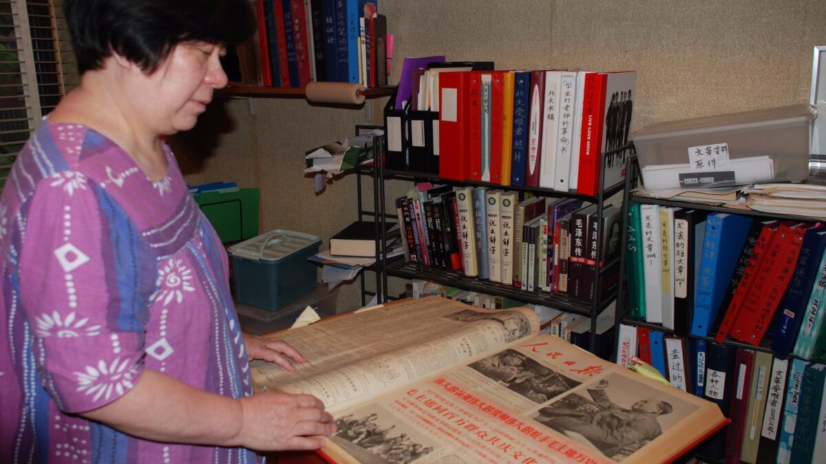 Wang Youqin in her Chicago home, looking through her collection of materials on the Cultural Revolution, including the People’s Daily, the Chinese Communist Party mouthpiece that chronicled the purges.