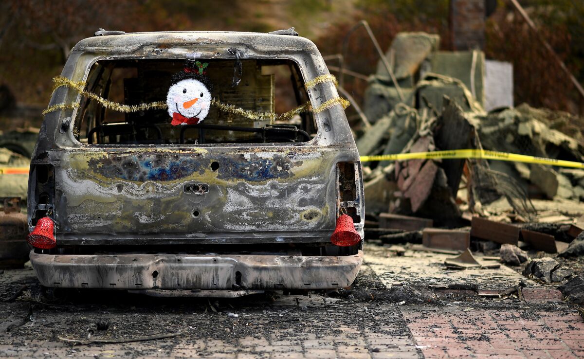 Christmas ornaments are hung from a burned car along High Point Drive in Ventura on Christmas Eve.