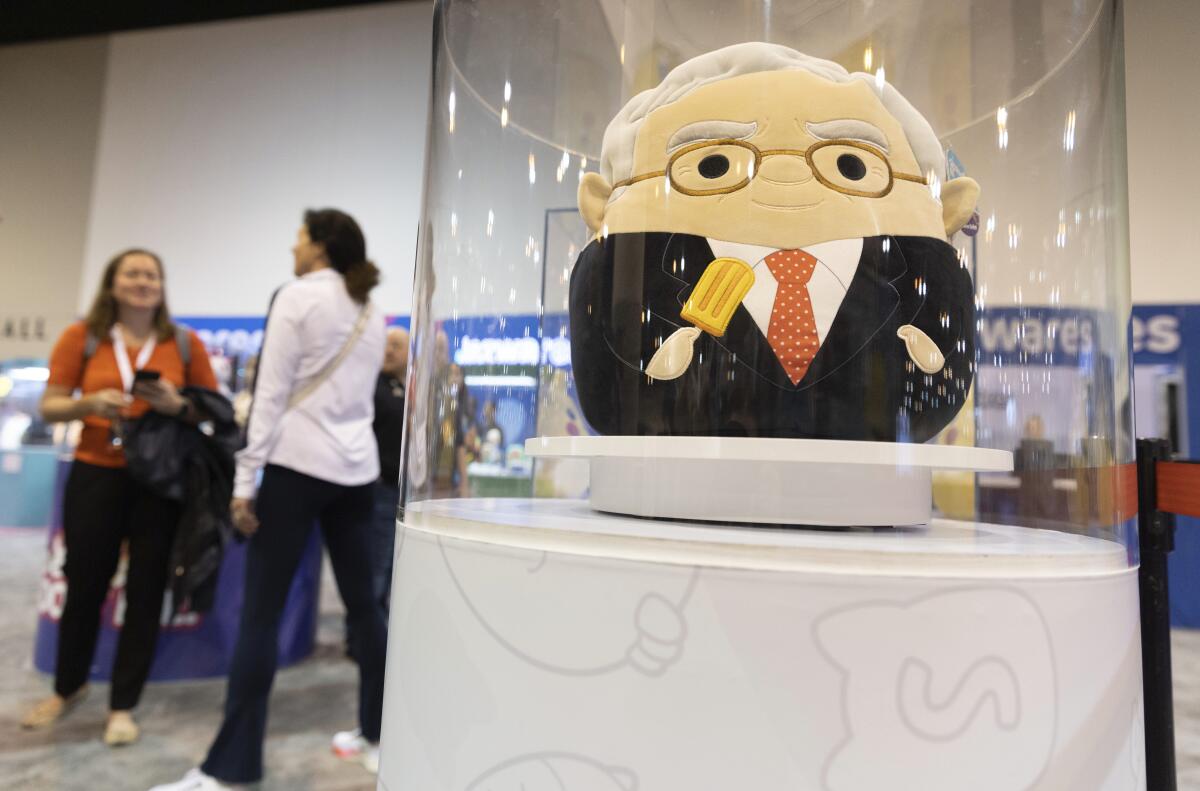 Two women stand near a Squishmallows toy modeled after billionaire Warren Buffett