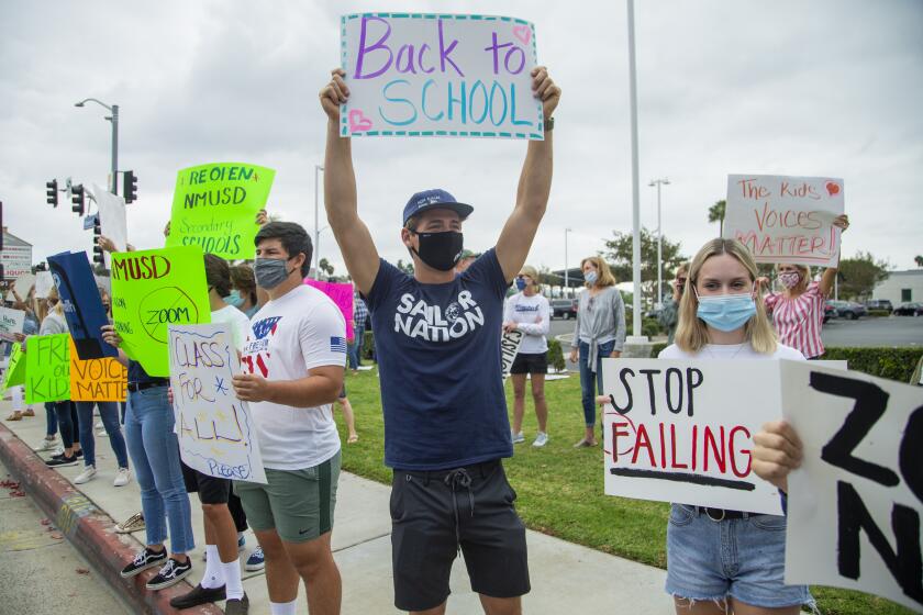 Prescott Cook, center, Grace OÕBrien and other students and parents protest outside the Newport-Mesa Unified School District office on Friday, October 23.