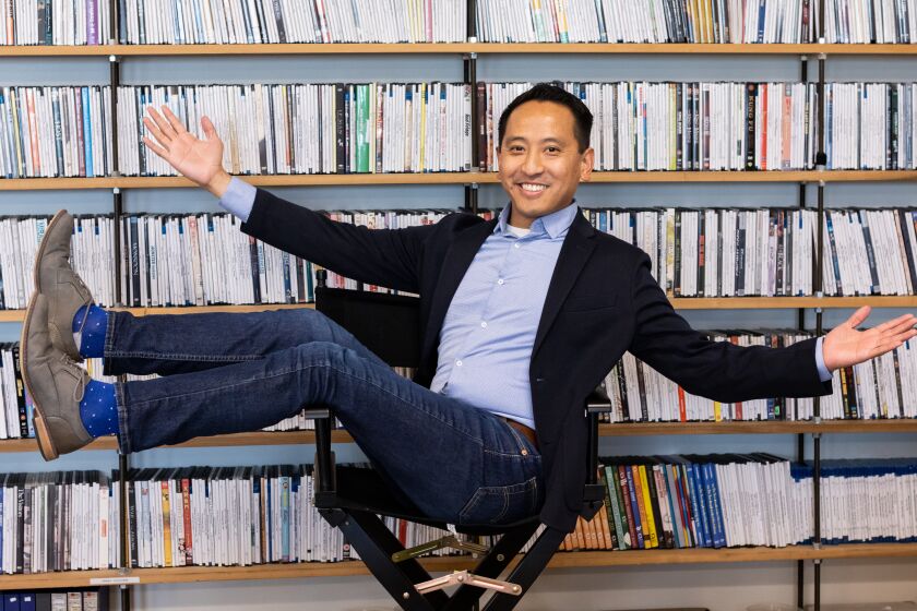San Diego, CA - March 13: Alex Villafuerte poses in front of Pacific Arts Movement's shelf of archived movies at its office on Thursday, March 16 in San Diego, CA. Villafuerte was named the executive director of the non-profit organization on February 20.
