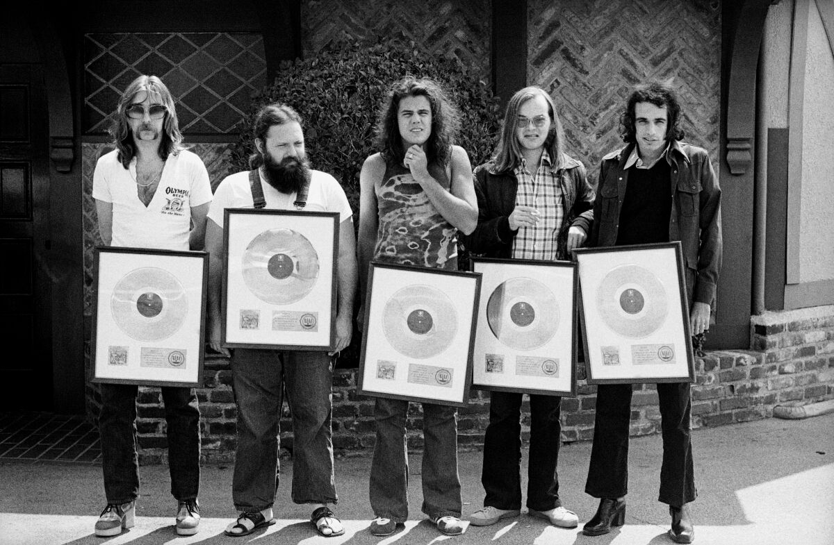 A rock band poses with a gold record in the '70s