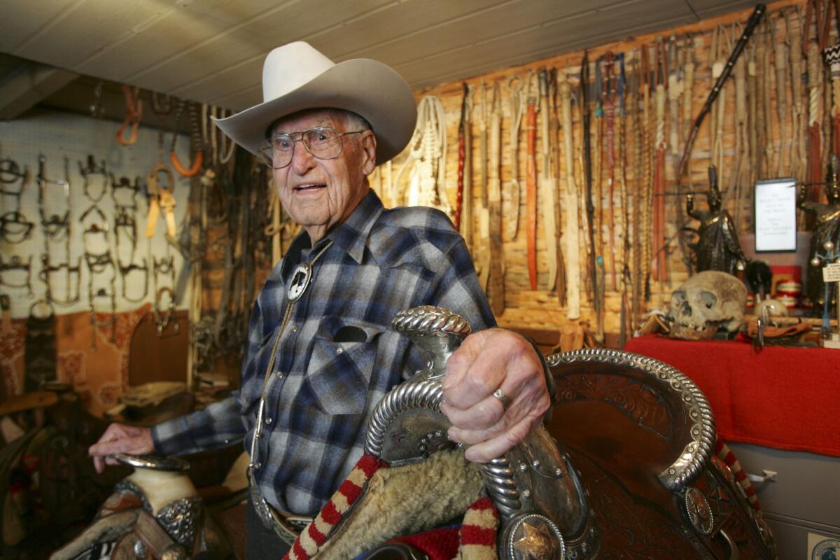 Man poses with western saddles 