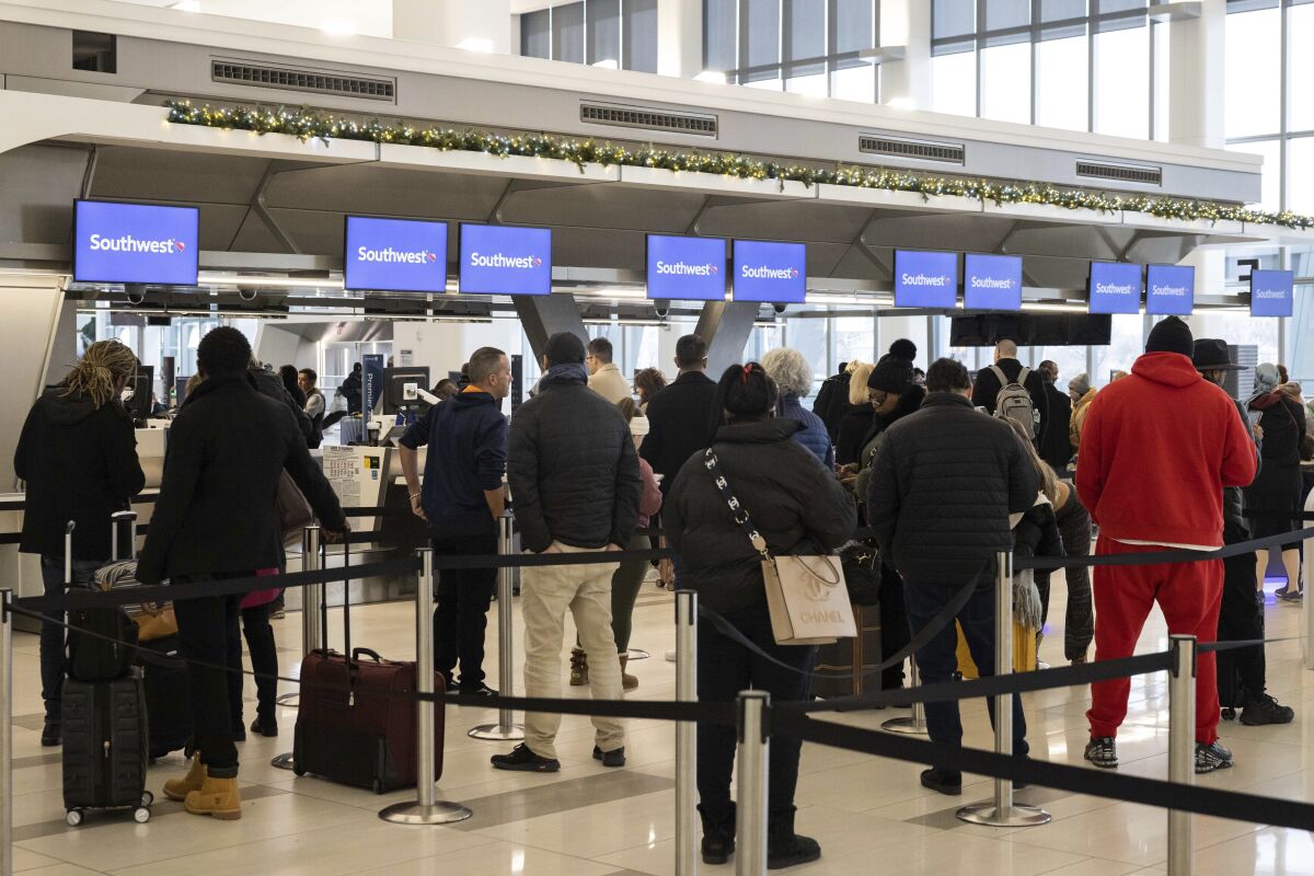 Passengers wait in line to check in for their flights at the Southwest Airlines service desk at LaGuardia Airport.