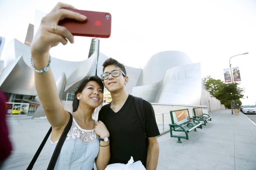 Madison Villanueva of Van Nuys uses her phone to take a photo of herself and Magdalenno Rosales of Los Angeles at Disney Hall.