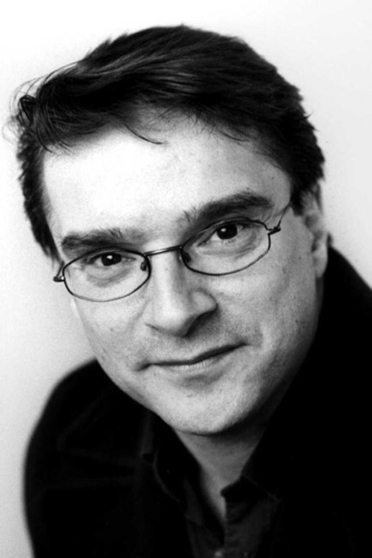 A black-and-white portrait of a man with dark hair wearing glasses.