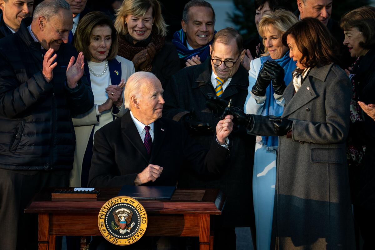 President Biden hands a pen to Vice President Kamala Harris at a signing ceremony