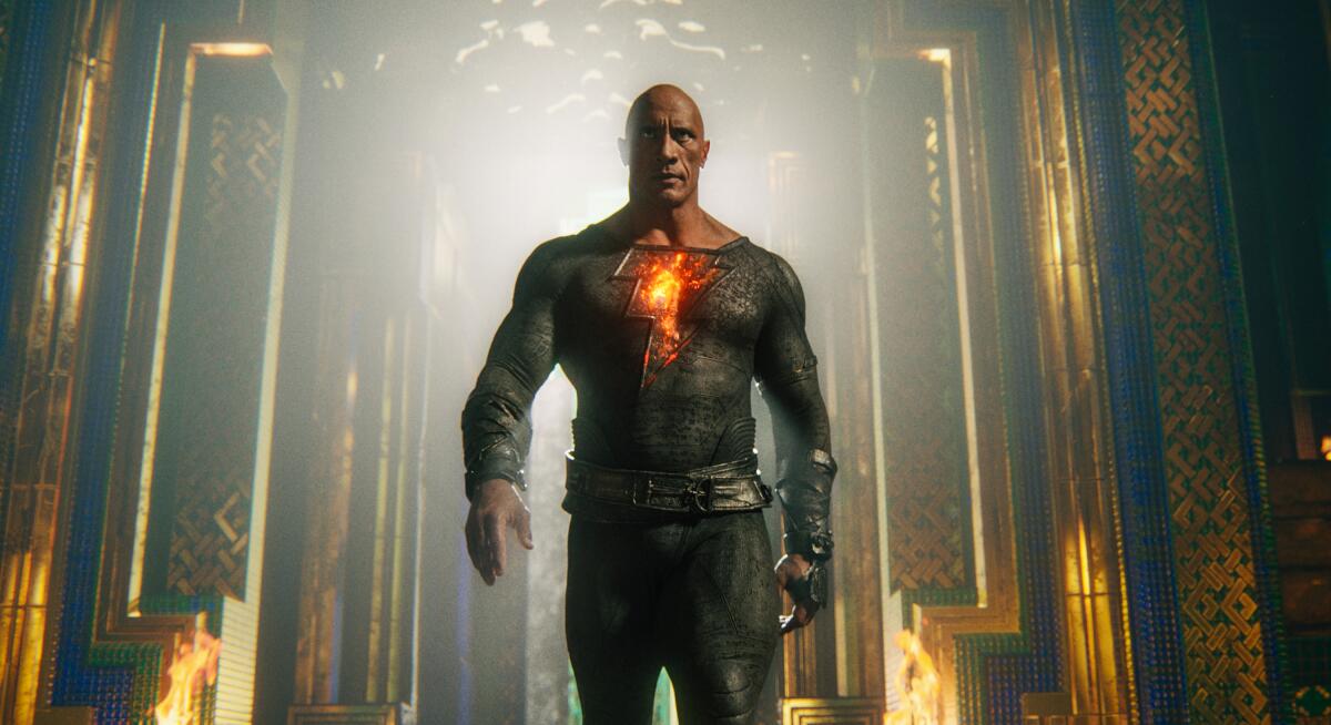 A muscular bald man in a superhero suit walking forward