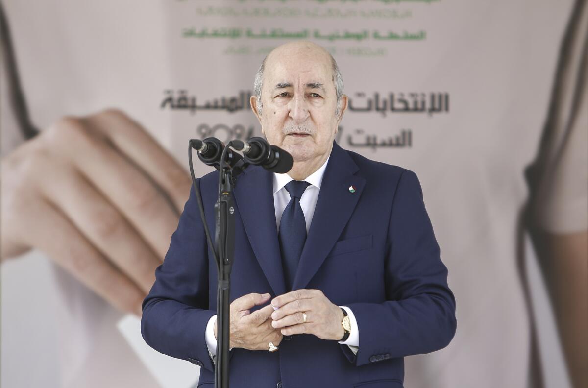 Algerian President Abdelmajid Tebboune in a suit in front of a microphone