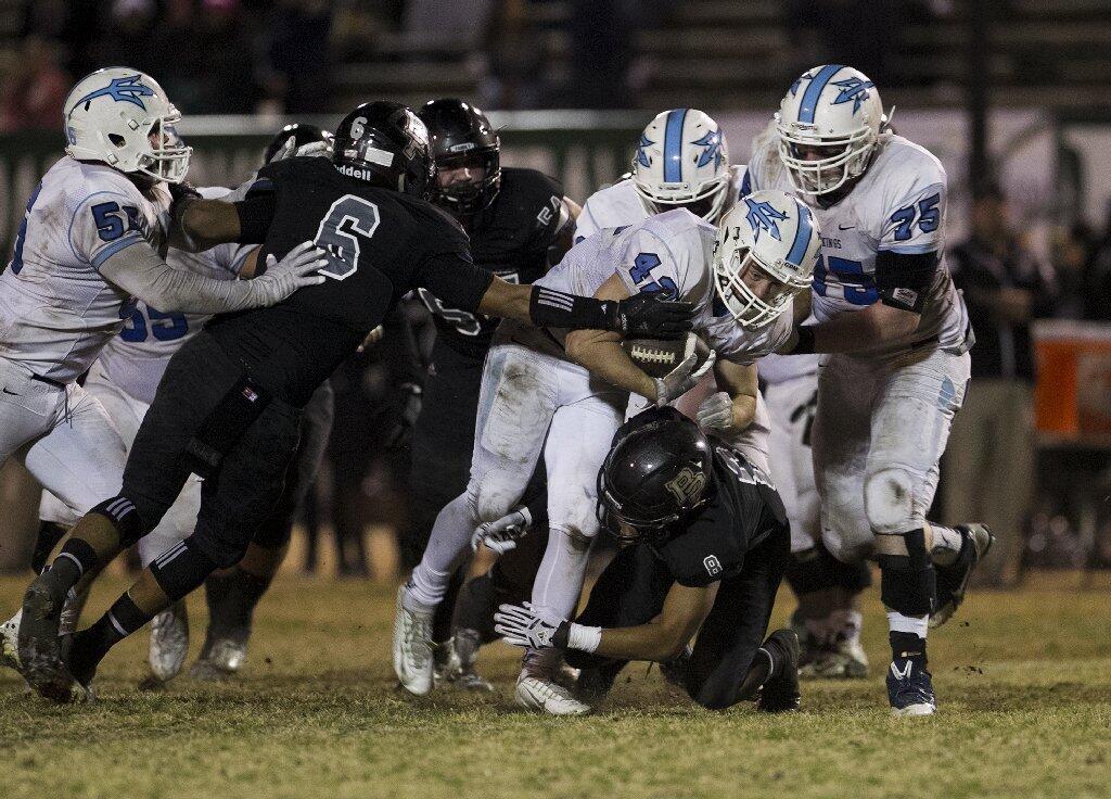 Corona del Mar High Jaydin Moses is brought down by Buena Park's Deshaun Harvey (8) and Alex Rojas.
