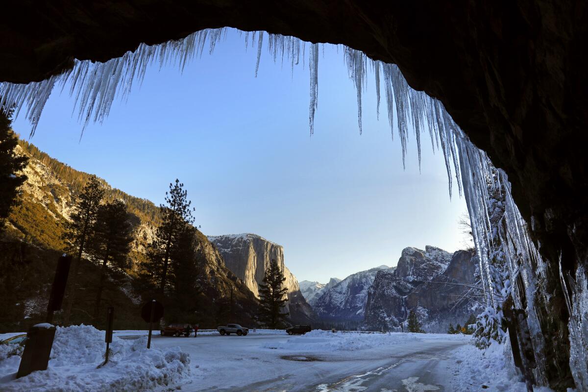 Icicles hang from Wawona Tunnel framing a view of Yosemite National Park lighted by afternoon light.