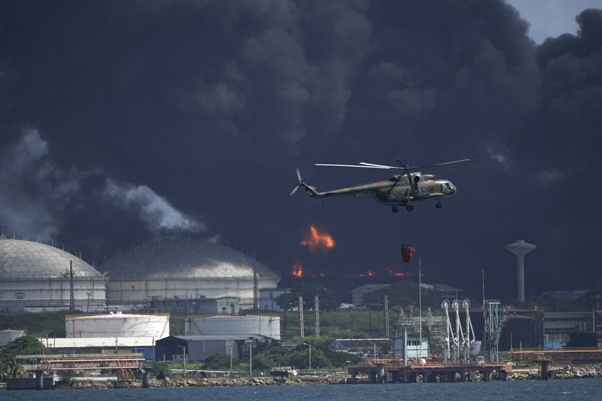 A helicopter flies against billows of black smoke.
