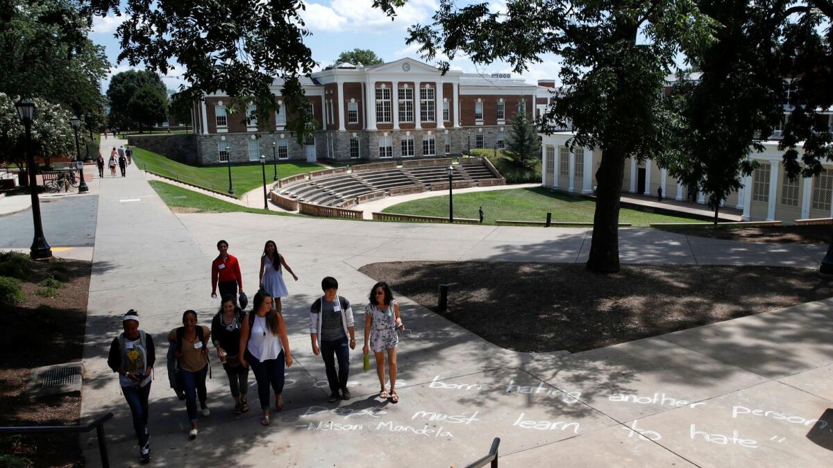 Students walks past a quote in chalk credited to Nelson Mandela at the University of Virginia in Charlottesville, Va. on Aug. 18, a week after a white nationalist rally took place on campus. The quote says "No one is born hating another person...people must learn to hate."
