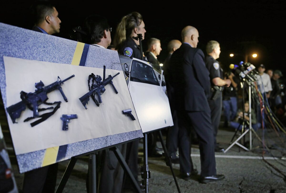 Police crime photos of assault rifles and handguns are displayed during a news conference 