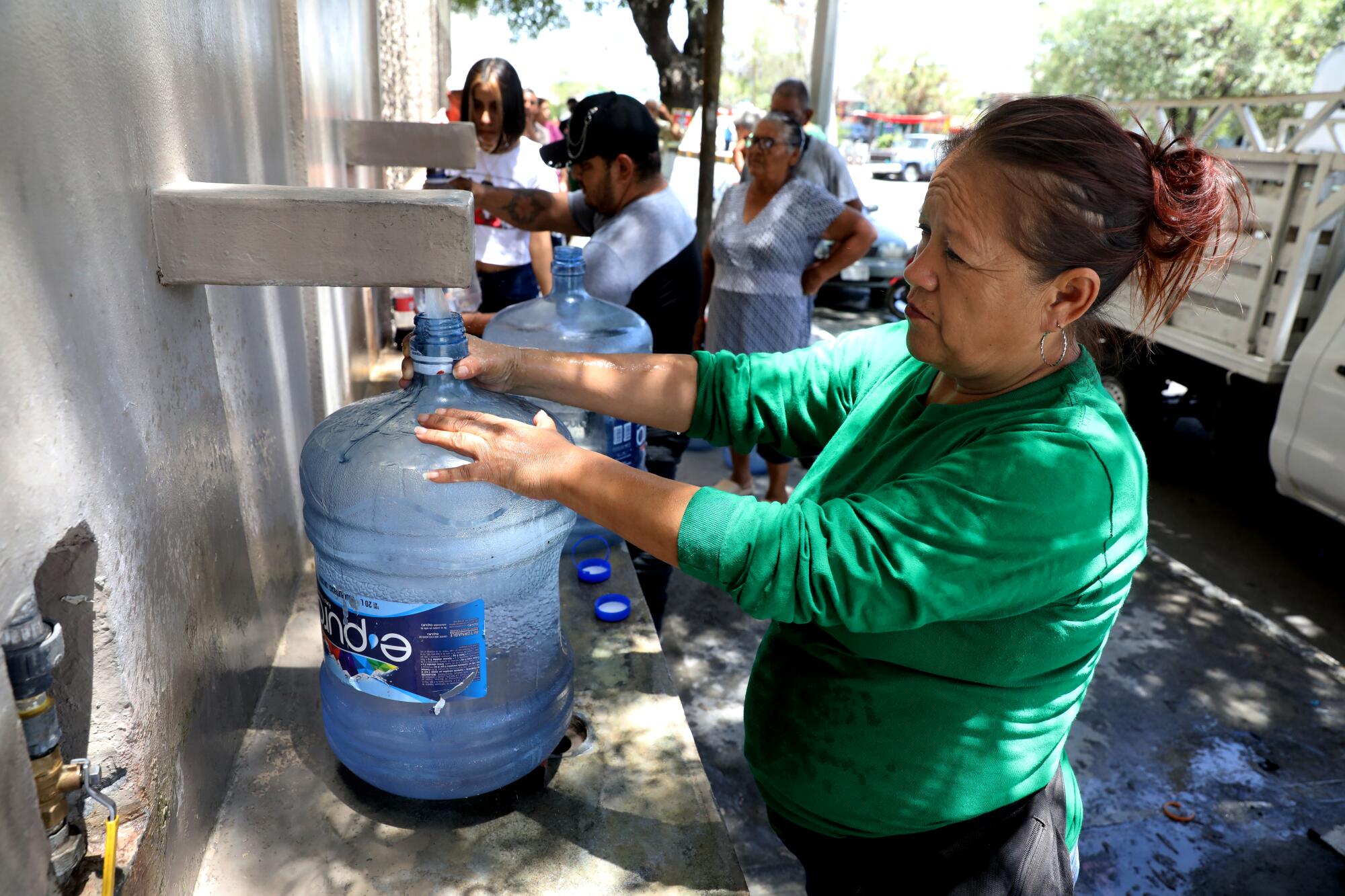 Maria del Carmen Hernandez fills bottles of free water outside the Topo Chico plant