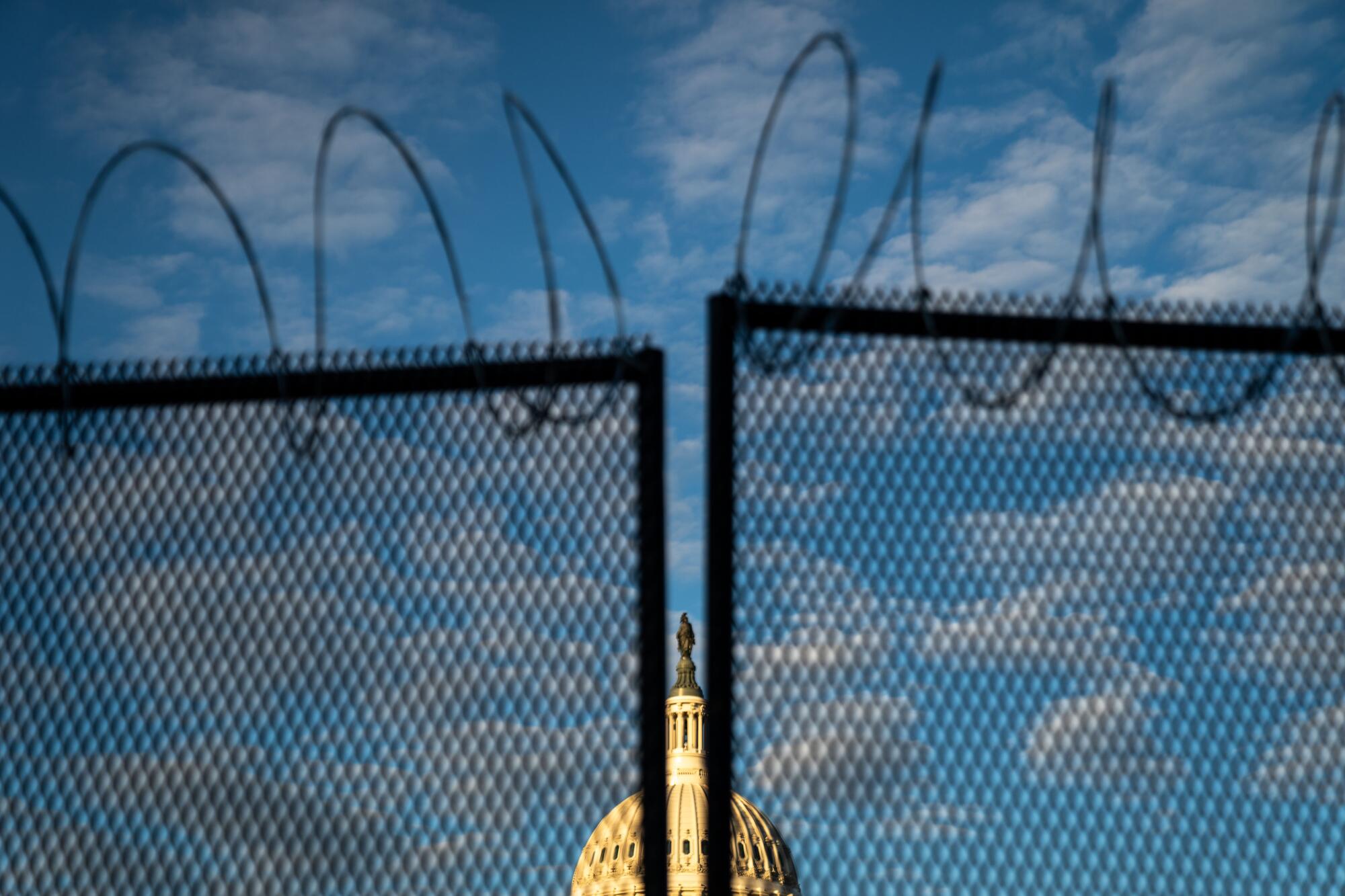  Barbed wire is seen atop security fencing, with the dome of the U.S. Capitol Building Saturday.