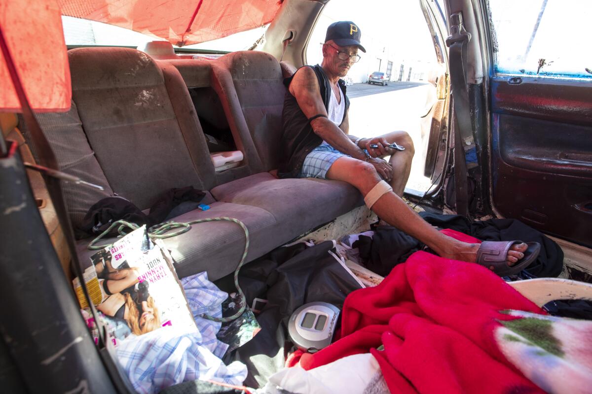 Homeless man Tam Nguyen passes time in his car in an alley near Moran Street in the Little Saigon community.