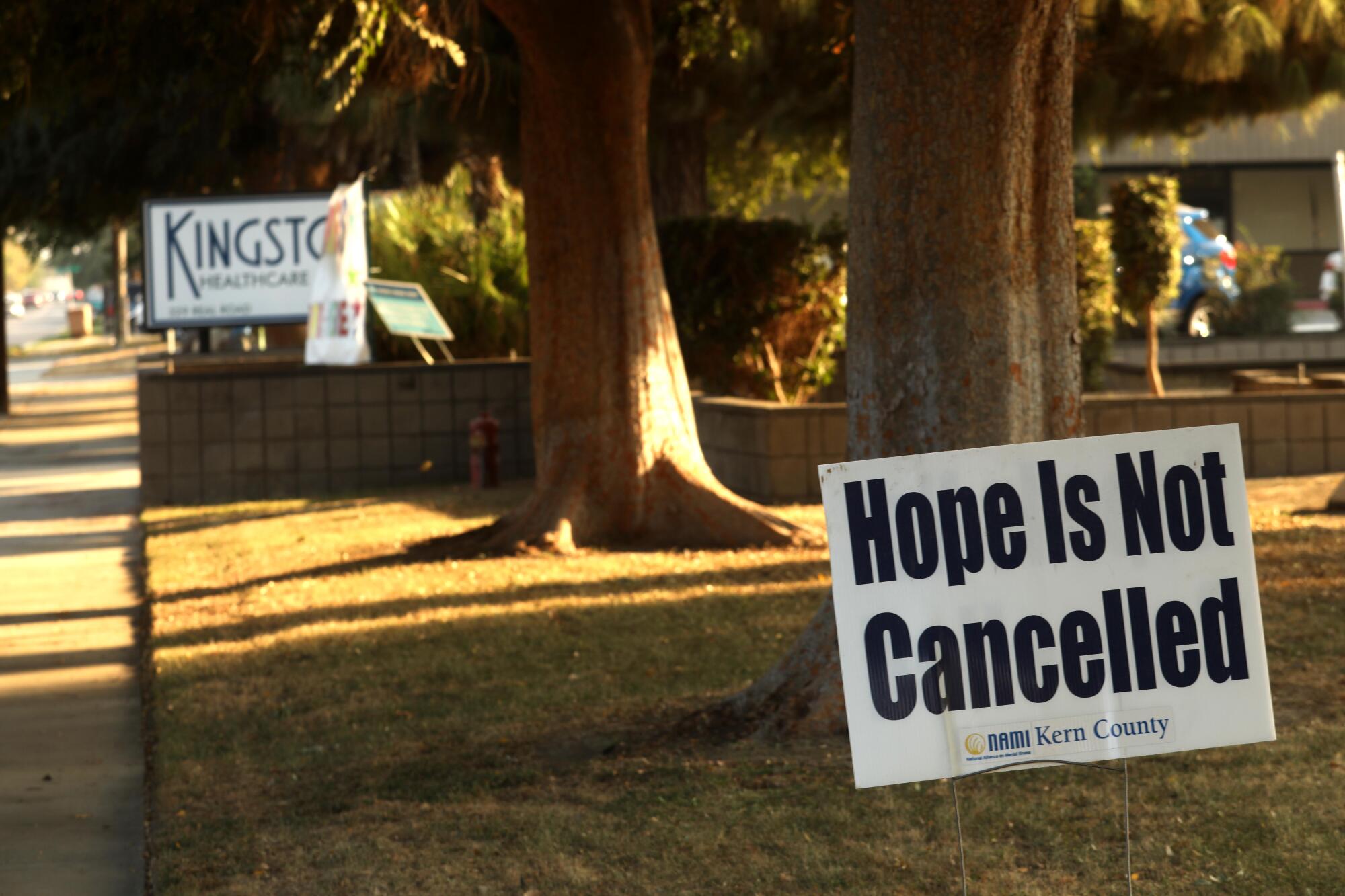 A sign staked on the grass outside Kingston Healthcare Center reads "Hope is not cancelled."