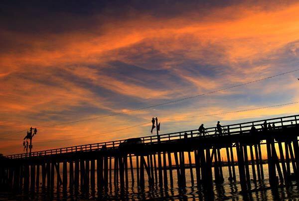 Cyclists ride on Stearns Wharf at sunset in Santa Barbara.