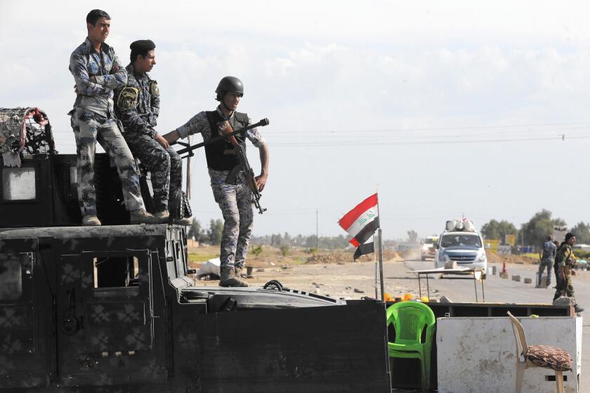 Iraqi police watch for cars at a checkpoint at the entrance of Alam, recently cleared of Islamic State fighters.