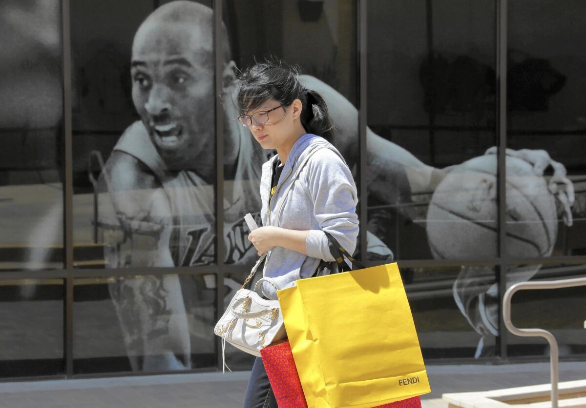 Retail sales ticked up only 0.1% from March to April, excluding motor vehicle and parts spending, which tends to be volatile. Above, a shopper walks past a store in Cabazon last year.