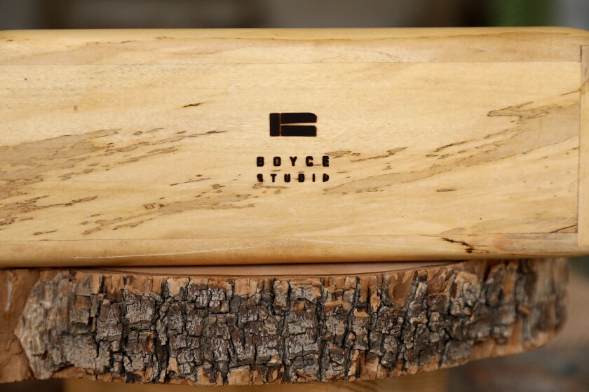 A Boyce Studio stamp in the bottom of a wood urn resting on top of a cross-section of a log.