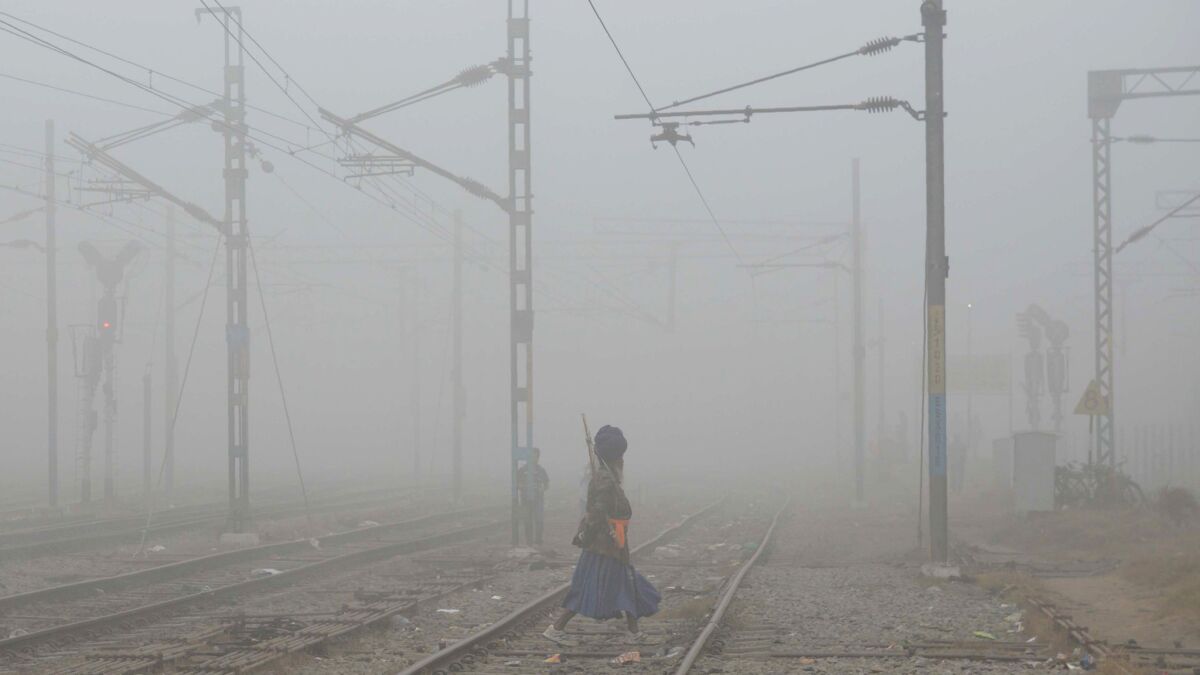 A Nihang, or traditional Sikh army member, crosses railway tracks amid dense smog near Amritsar railway station.