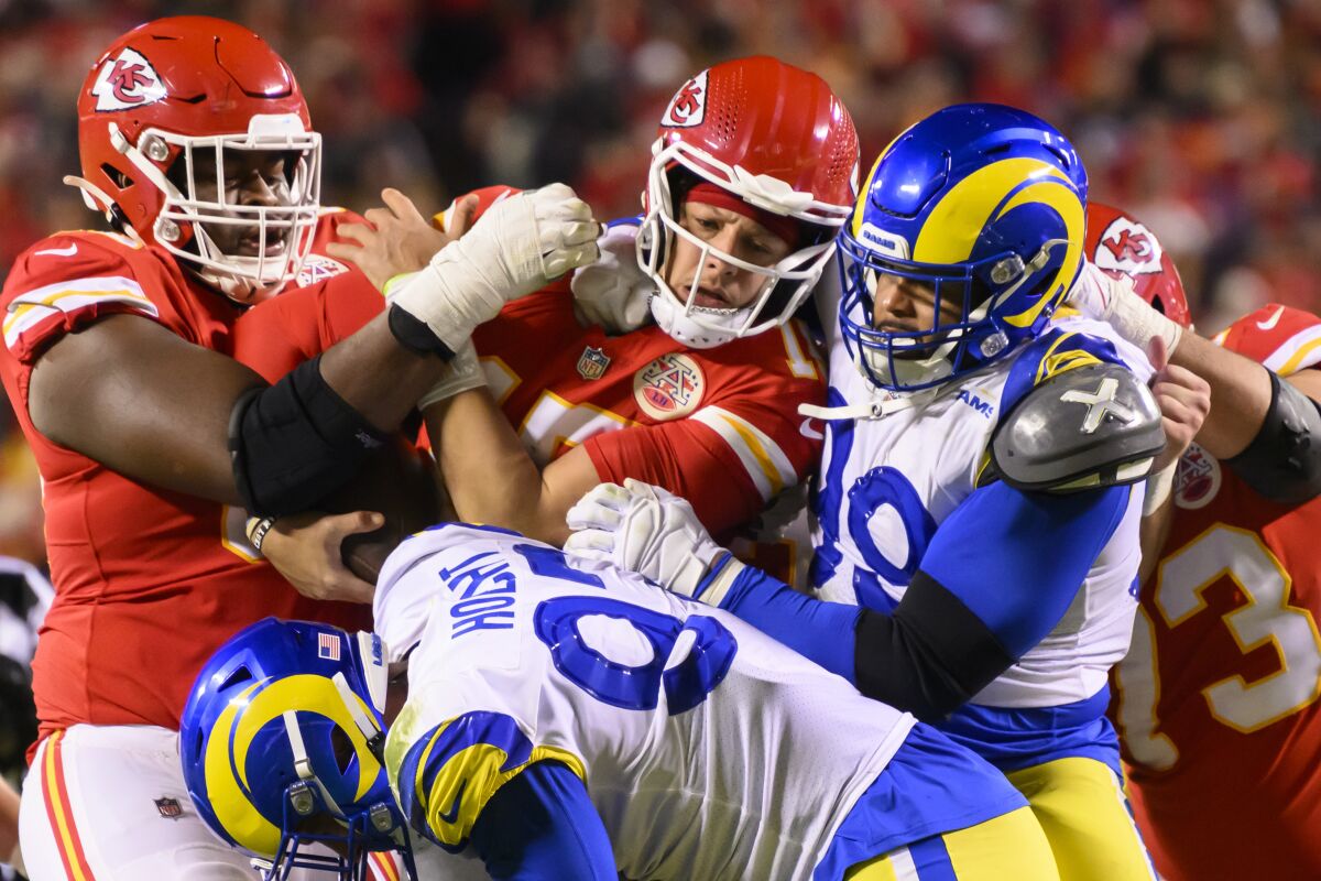 Chiefs quarterback Patrick Mahomes (center) is tackled by Rams Michael Hoecht (97) and Aaron Donald (99).