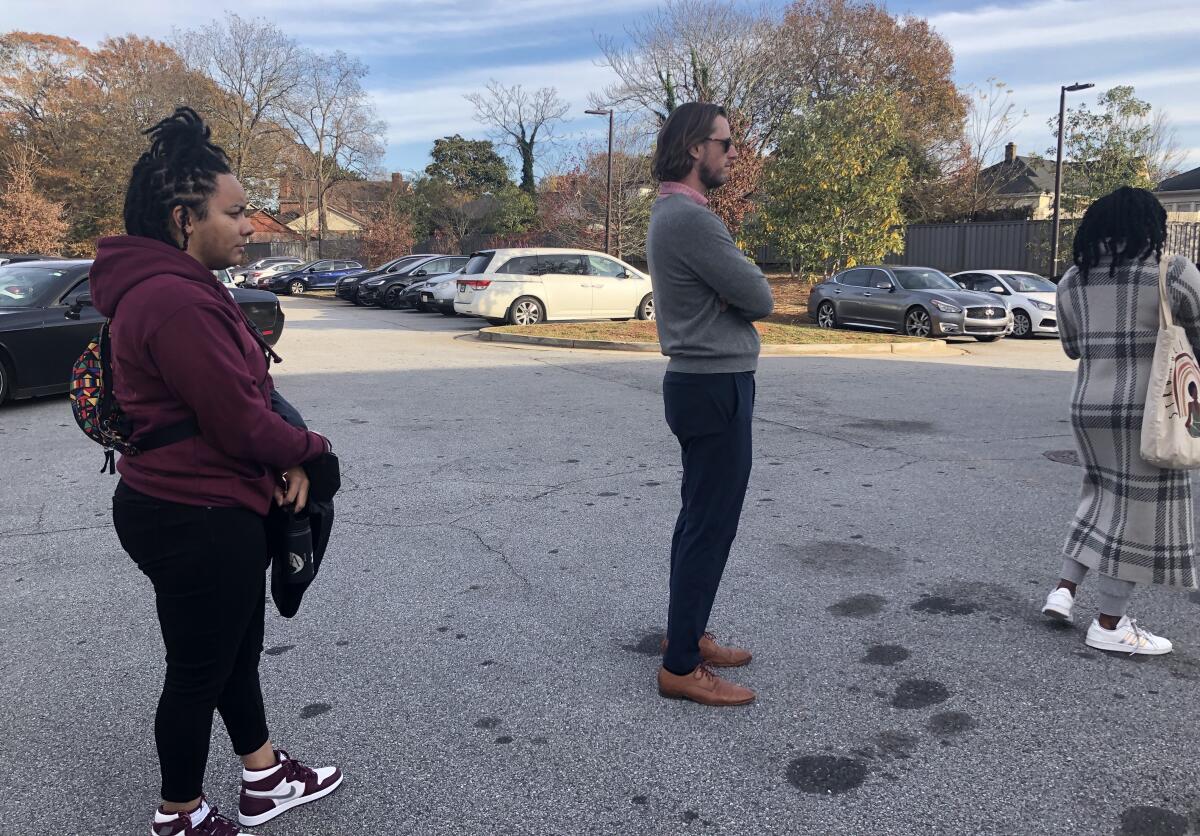 Voters stand in line in a parking lot outside a library polling station. 