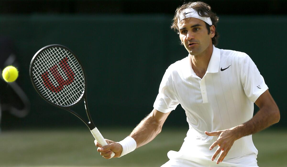 Roger Federer volleys a shot back at Milos Raonic during their semifinal match at Wimbledon on Saturday.