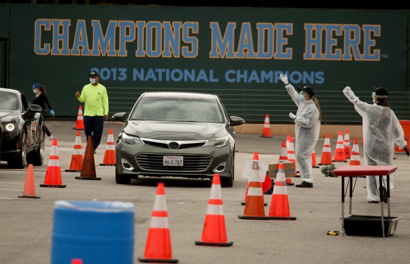 Workers direct drivers at a test site for COVID-19 at a Veterans Administration parking lot in Los Angeles on April 7, 2020.