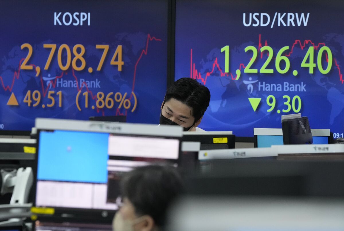 A currency trader watches monitors in front of screens showing the Korea Composite Stock Price Index (KOSPI) and the foreign exchange rate between U.S. dollar and South Korean won, right, at the foreign exchange dealing room of the KEB Hana Bank headquarters in Seoul, South Korea, Thursday, March 17, 2022. Asian stock prices have surged for a second day after the Federal Reserve announced its first interest rate hike since 2008 and China promised support for its real estate and internet industries. (AP Photo/Ahn Young-joon)