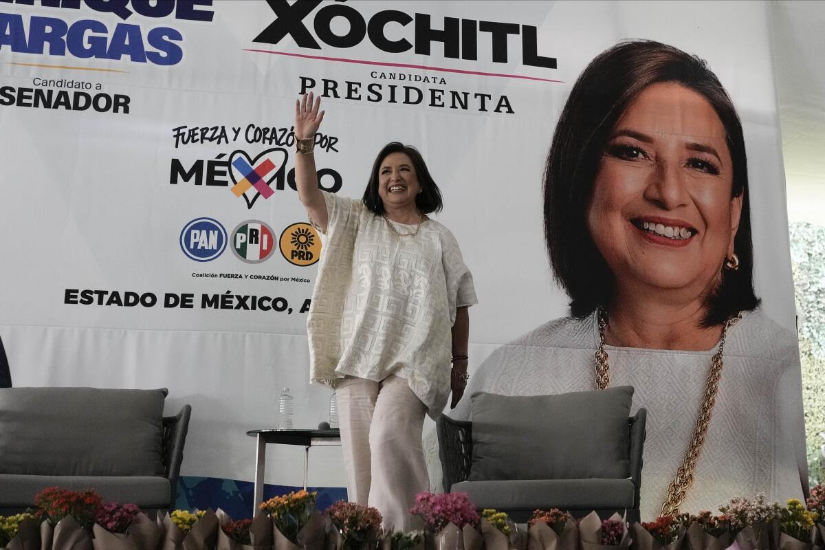 Xóchitl Gálvez waves in front of a banner with her face and name.
