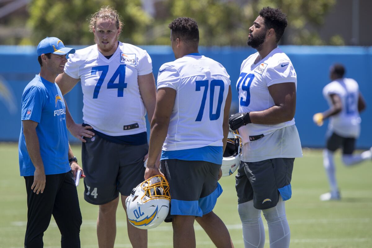 Chargers coach Brandon Staley talks with tackles Storm Norton (74), Trey Pipkins III (79) and Rashawn Slater (70).