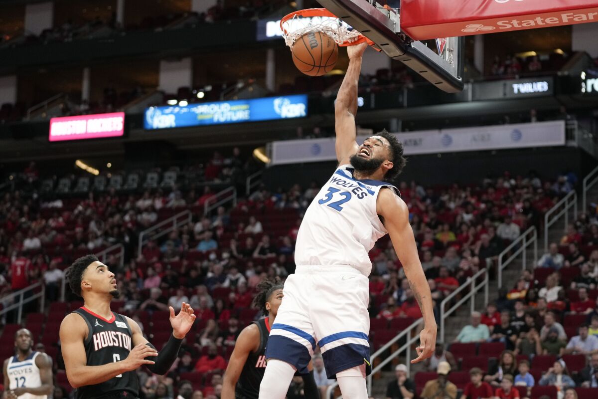 Minnesota Timberwolves center Karl-Anthony Towns (32) dunks as Houston Rockets forward Kenyon Martin Jr., left, watches during the first half of an NBA basketball game, Sunday, April 3, 2022, in Houston. (AP Photo/Eric Christian Smith)