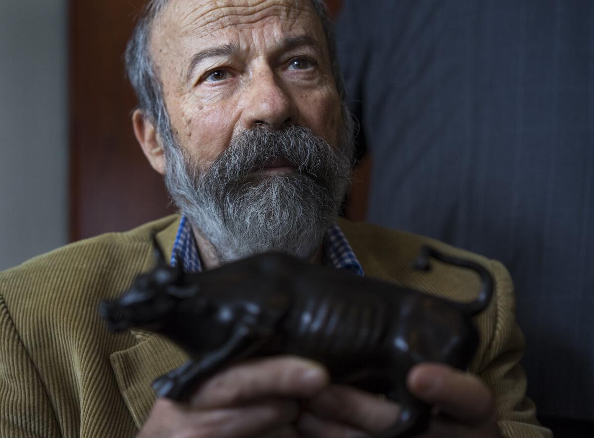 Arturo Di Modica holds a model of his 'Charging Bull' sculpture. 