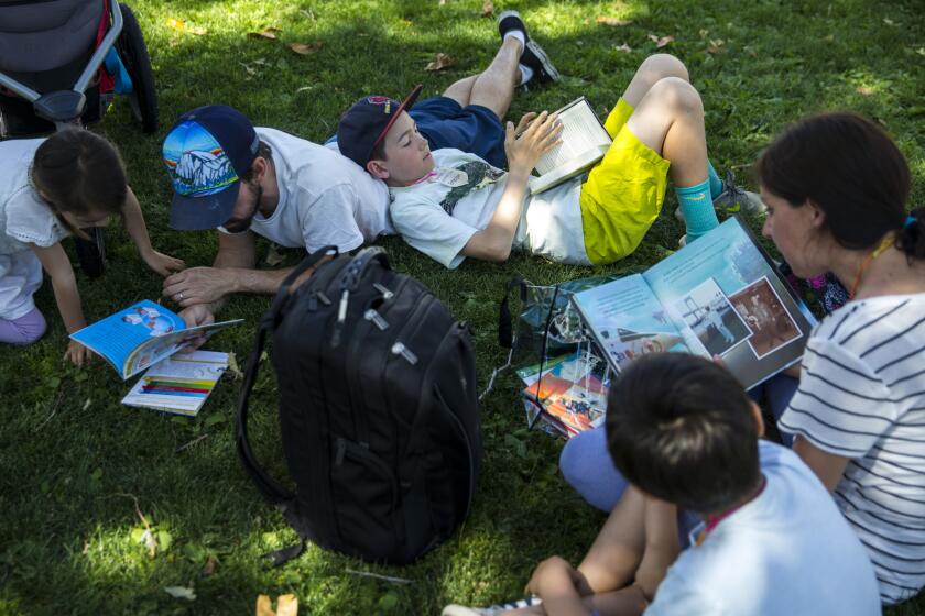LOS ANGELES, CALIF. - APRIL 22: Aurora Carrillo-Vincent, 5, Matthew Carrillo-Vincent, 35, Emerson Carrillo-Vincent,11, Christine Carrillo-Vincent, 35, and Atticus Carrillo-Vincent, 7 , read together during the annual Los Angeles Times Festival of Books at the University of Southern California on Sunday, April 22, 2018 in Los Angeles, Calif. (Kent Nishimura / Los Angeles Times)