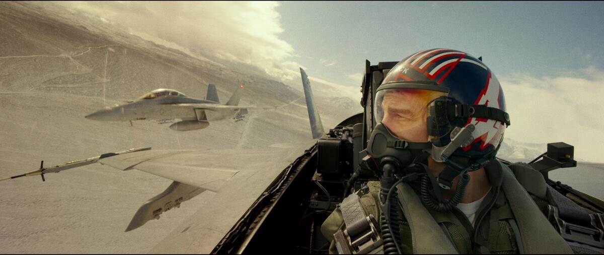 A fighter pilot looks over his shoulder at a fighter jet alongside his.