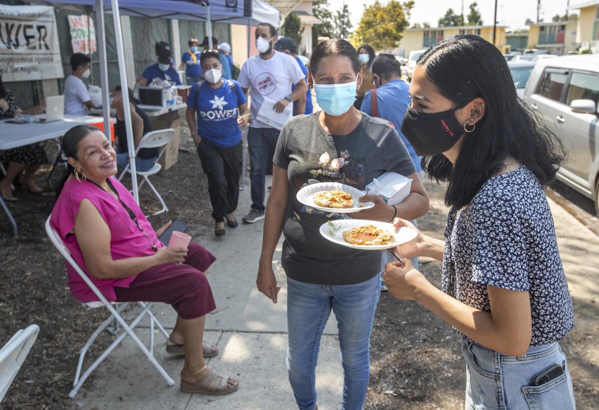 Maria Salcedo, center, and her daughter Maribel, 17, at a community fair in Pacoima.