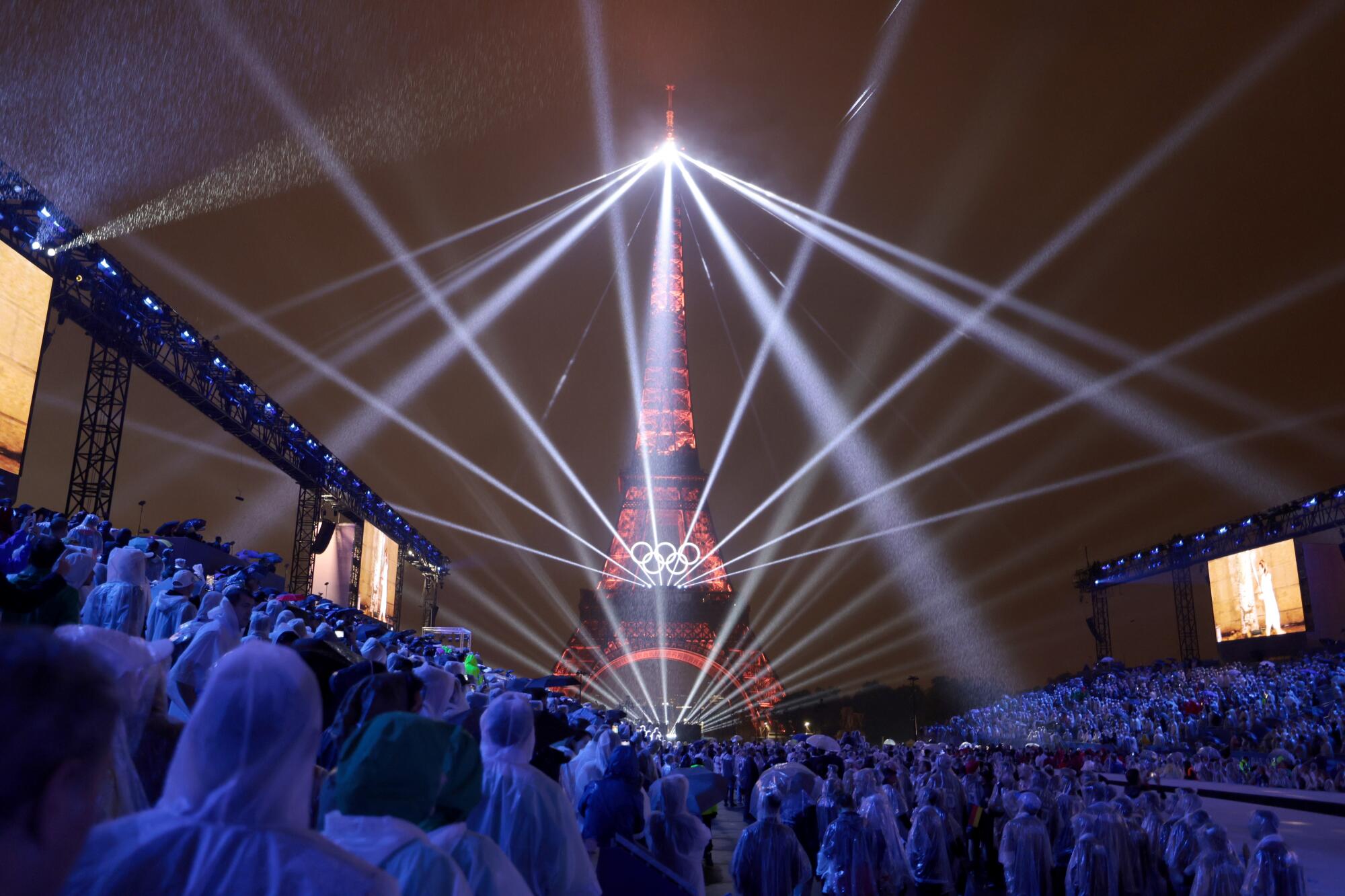 Lasers projecting from the Eiffel Tower at night.