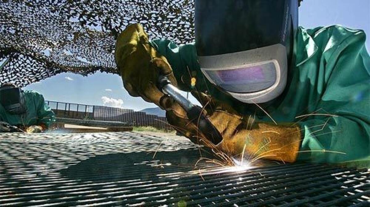 National Guardsman Stephen Hammon, 40, welds double-steel-mesh panels together for the new fence west of Naco, Ariz.