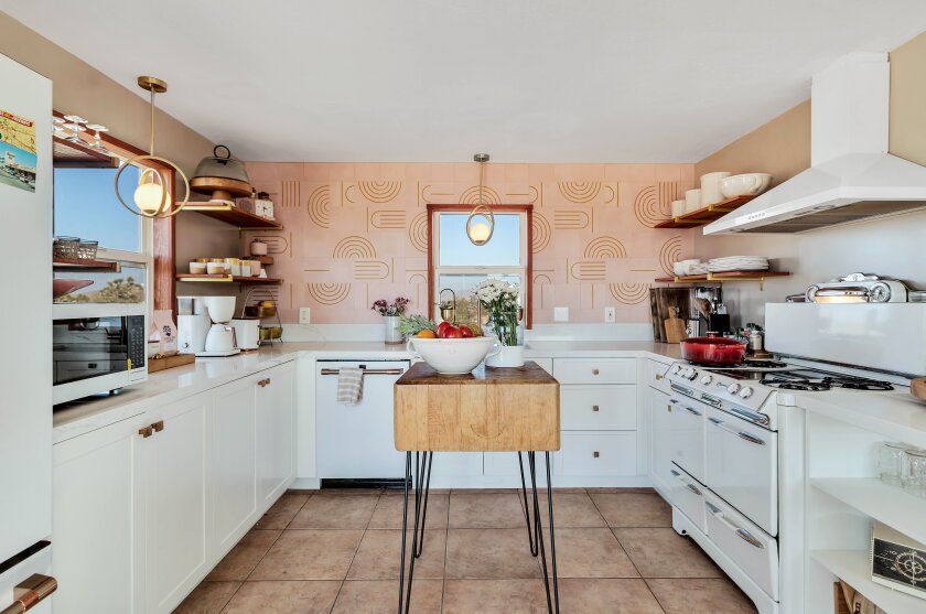 A kicthen with a backsplash of patterned tile and a wooden island on metal legs