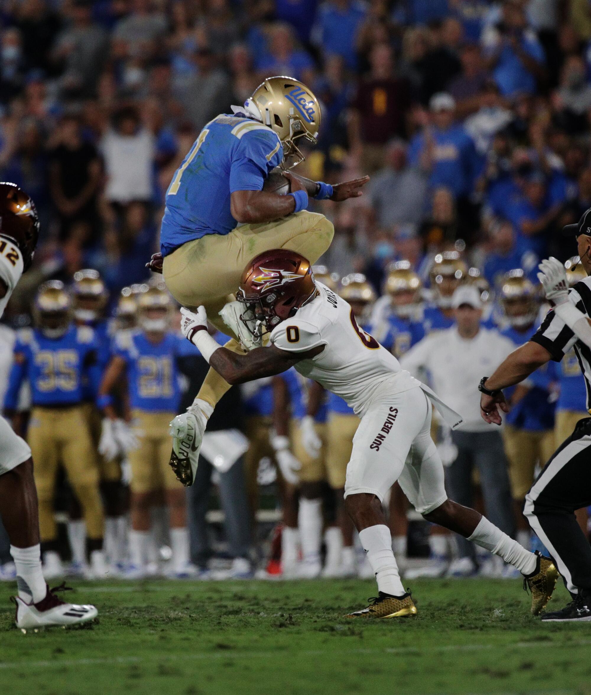 UCLA quarterback Dorian Thompson-Robinson tries to leap over Arizona State defensive back Jack Jones in the first half.