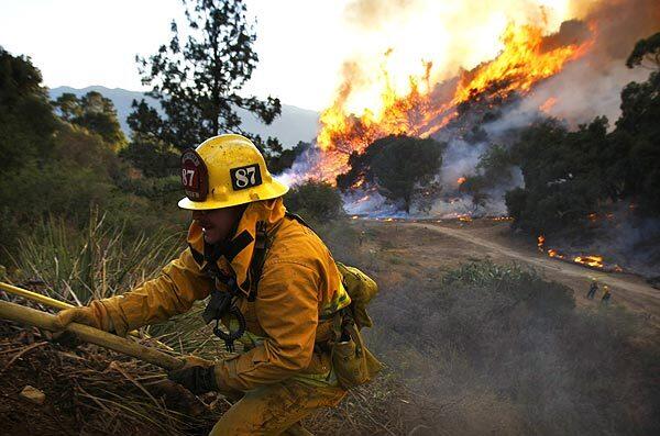 A firefighter climbs up a hose after a backfire is lit in La Crescenta.