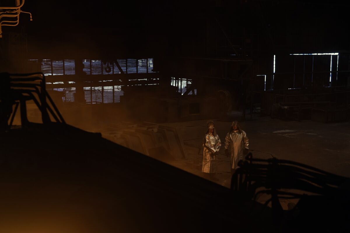 Workers stand inside a blast furnace at the Zaporizhstal steel plant, in Zaporizhia, Ukraine, Wednesday, March 1, 2023. The southwestern city of Zaporizhzhia, which gives the plant its name, is less than 50 kilometers (31 miles) from the front line and its residential buildings and energy infrastructure are a frequent Russian target. The impact of the war has left the plant running below full capacity, with a third of its 10,000 workers idle. (AP Photo/Thibault Camus)