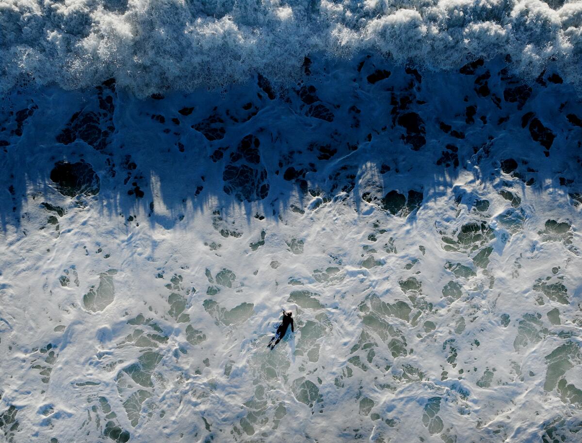 A surfer struggles to paddle against strong currents in Huntington Beach on Jan. 4.
