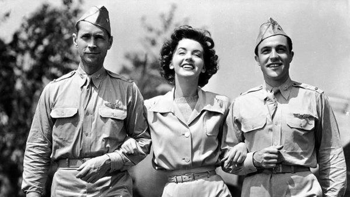 Marsha Hunt links arms with actors Franchot Tone and Gene Kelly, all in military uniforms.