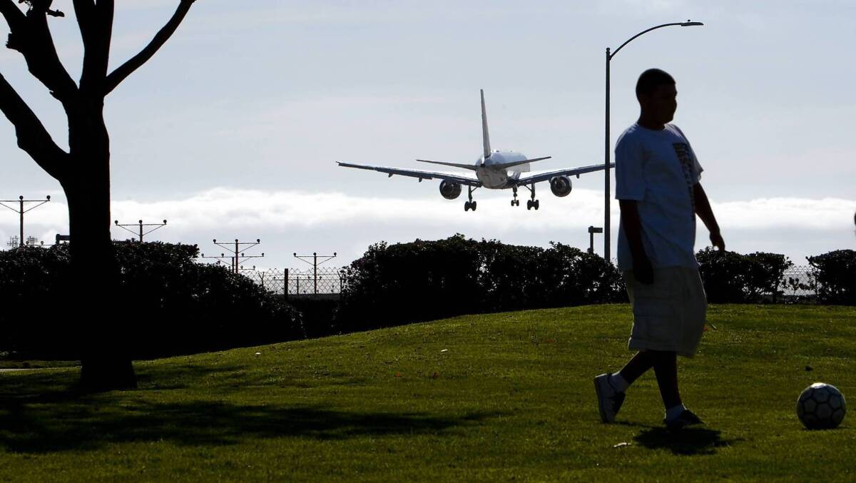 A youngster kicks a soccer ball as a plane lands on the north runway at Los Angeles International Airport. Several lawsuits have been filed that challenge a plan to relocate the north runway closer to homes.