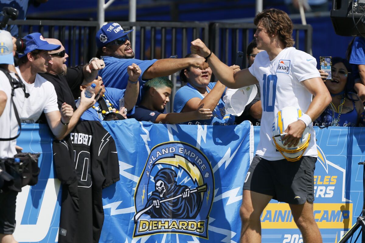  Chargers quarterback Justin Herbert high-fives fans after the first day of training camp.